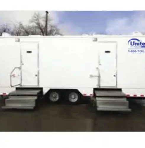 White mobile shower trailer exterior parked outdoors with two metal steps leading to separate doors