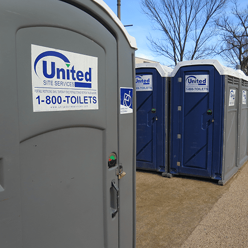 Row of blue and gray portable toilets in an outdoor setting