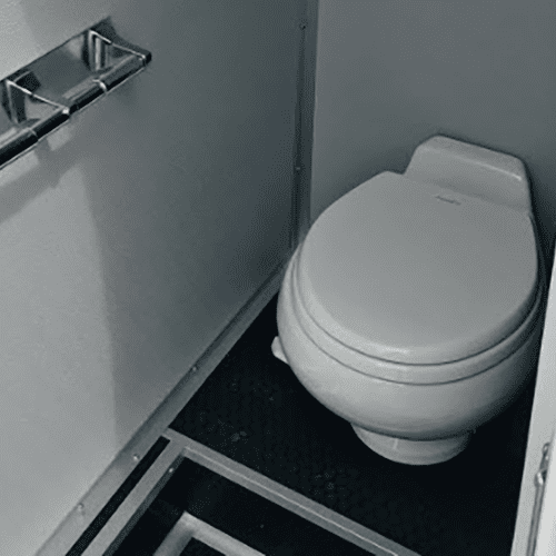 Interior of a solar-powered restroom trailer with a toilet and a toilet paper rack, viewed from above