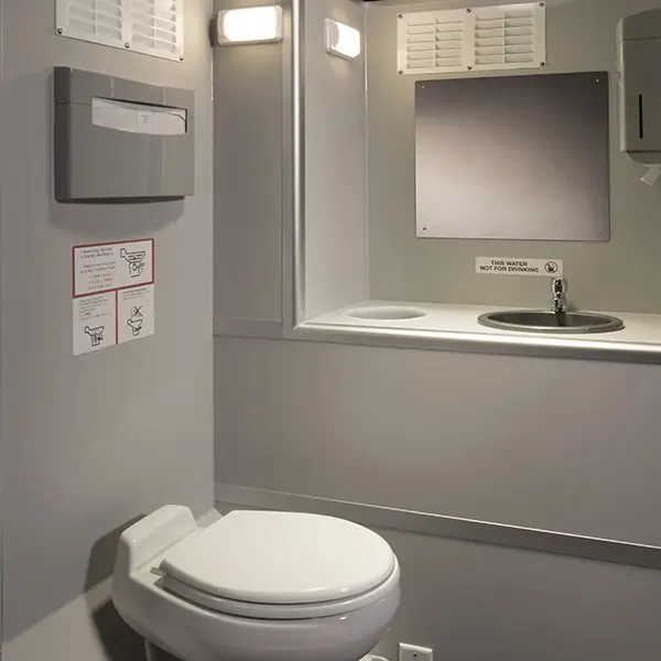 A small, clean bathroom with a closed toilet seat, a sink, paper towel dispenser, and a mirror