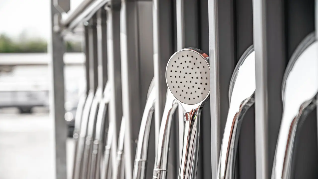 A row of shiny silver Hydroflow shower heads installed along a wall